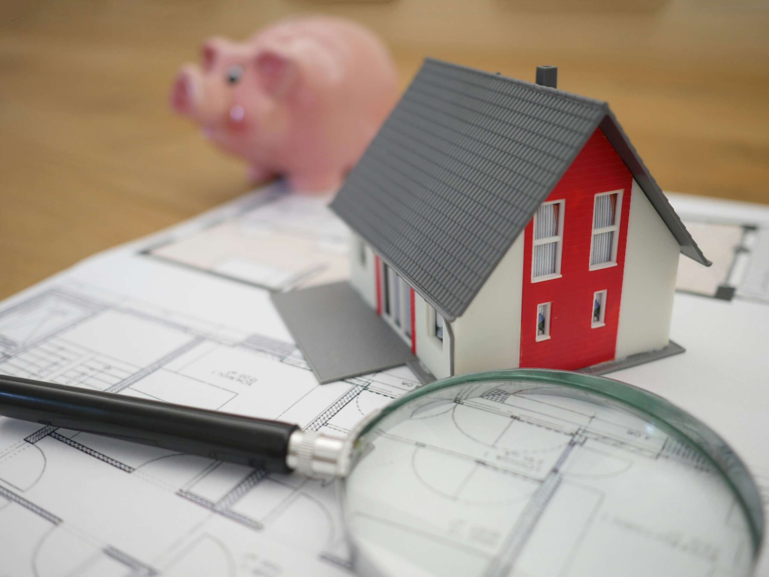Maison en bois rouge et blanc à côté d'une loupe à cadre gris